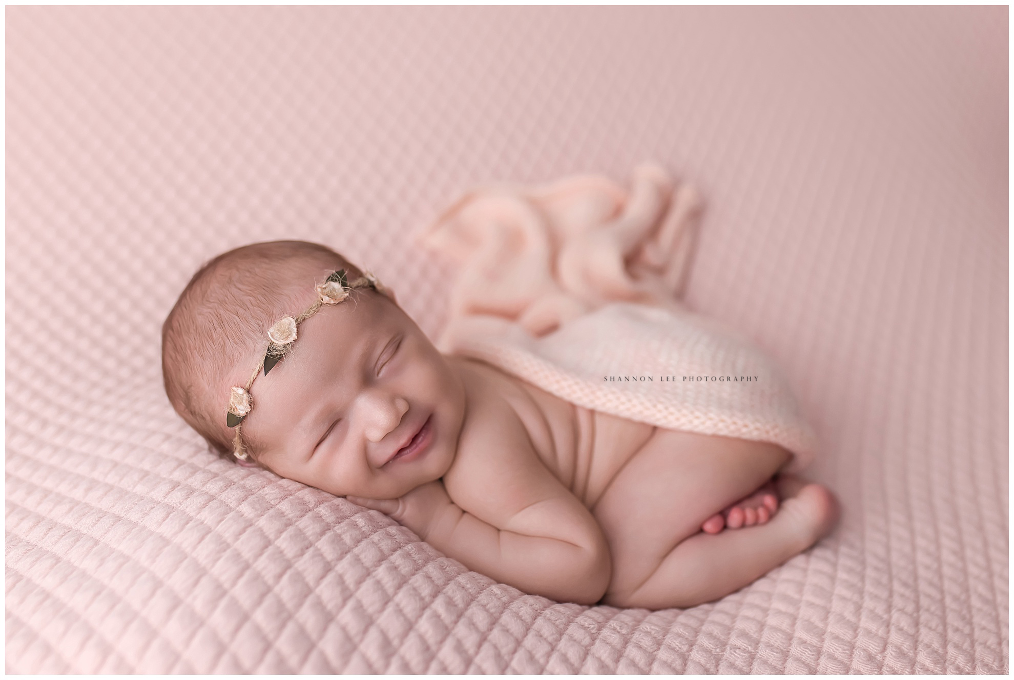 Newborn baby girl in ballet pink with a smile
